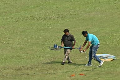 Groundsmen use a fan to dry a patch of wet outfield