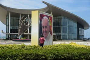 A man walks next to a giant portrait of Pope Francis at the APEC Haus in Port Moresby