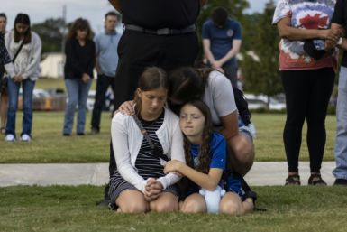 A mother and her children bow their heads in prayer at a vigil for the victims of the Apalachee High School shooting in Winder, Georgia