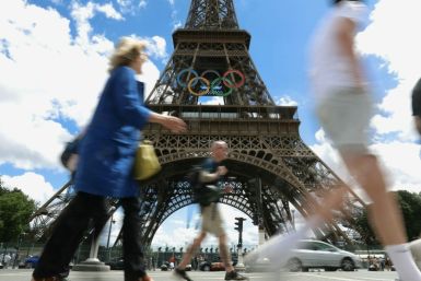 Pedestrians walk past the Eiffel Tower adorned with the Olympic Rings ahead of the 2024 Olympic Games in Paris in July 16, 2024.