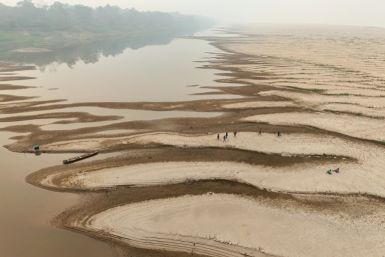 People carry drinking water along a sandbank of Madeira River in Paraizinho Community, in Humaita, Amazonas state, northern Brazil, on September 7, 2024