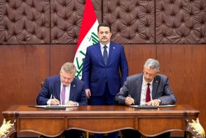 A picture released by the media office of Iraqi Prime Minister Mohamed Shia al-Sudani shows him  looking on as BP CEO, Murray Auchincloss (L) and Iraqi Oil Minister Hayan Abdul Ghani al-Sawad sign a memorandum of understanding to develop oil and gas field