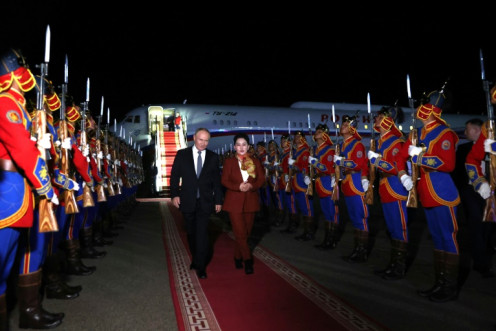 Russian President Vladimir Putin (L), accompanied by Mongolian foreign affairs minister Battsetseg Batmunkh, walks past an honour guard at Ulaanbaatar's airport Monday night
