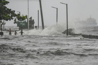 Youngster frollick in a storm surge along Manila Bay during heavy rain brought by Tropical Storm Yagi